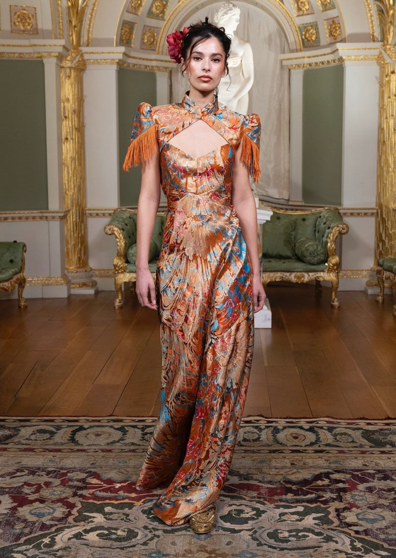 A floor-length draped gown in apricot brocade on the runway
